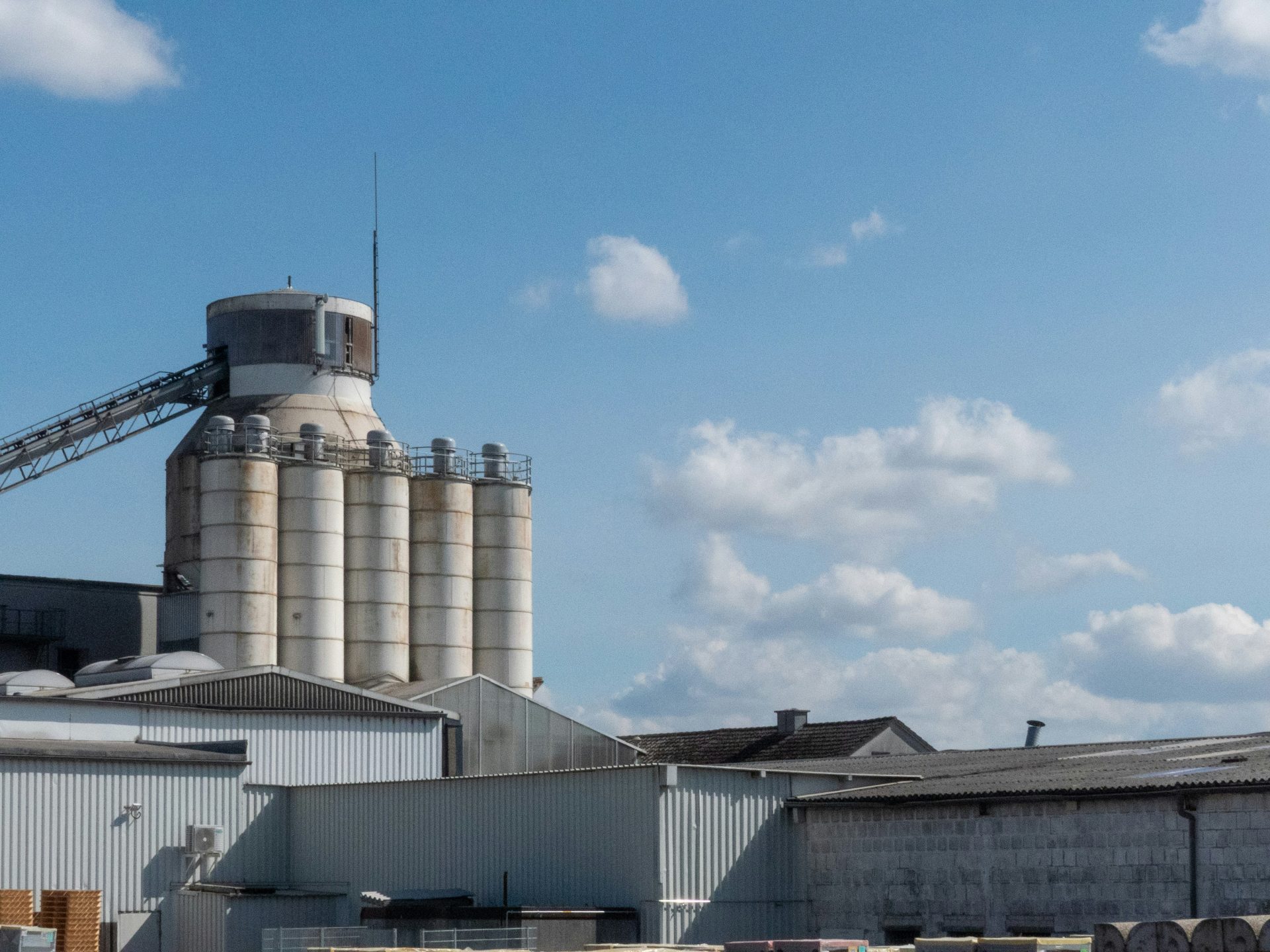 An industrial silo stands tall under a cloudy sky.