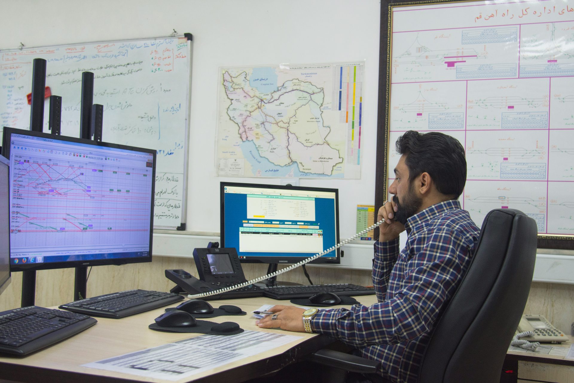 a man sitting at a desk talking on a phone